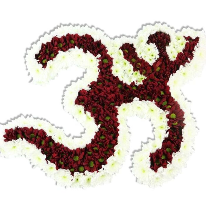 Set against an immaculate white background, this large floral depiction of the Om (Aum) sign is a study in contrast and devotion: a dense core of deep maroon chrysanthemums shapes the symbol's characteristic curves while a thick, flowing border of snowy spray chrysanthemums crisply defines its edges. The maroon blooms, small and pompon-like, are placed so tightly that the surface becomes almost velvet - each blossom revealing a small lime-green centre that catches the eye like specks of light across a dark field. The white outline snakes through the negative spaces, carving the inner loops and enhancing the calligraphic quality of the symbol. A soft drop shadow under the arrangement lifts it from the white plane and hints at the three-dimensional work involved in mounting such an intricate form. The tactile impression is immediate: imagine cool, layered petals and a subtle, grounding scent - a modest, earthy perfume that suits quiet reflection. This composition is designed with ceremony in mind, equally at home on a temple table, as the focal point of a memorial, or as a reverent installation at a spiritual gathering in Silvertown or near the Royal Docks community spaces. The craftsmanship reveals patient hands and disciplined technique, each bloom chosen and set to communicate respect and serenity. Colour and texture here are symbolic as well as visual: the rich maroon evokes depth, the pure white halo suggests peace, and the tiny lime centres add a living, natural accent. Seen through the perspective of an East London florist, this Om arrangement ties traditional iconography to contemporary floral artistry, offering a composition that honors ritual, memory, and quiet celebration.