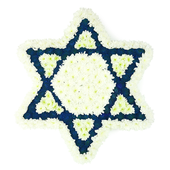 A striking Star of David funeral tribute fills the frame, rendered entirely in fresh, small-petalled flowers arranged with great care and intention. Against a plain, bright white backdrop, the six-pointed Magen David appears almost suspended, its edges softened by a thick, cloud-like rim of white chrysanthemums that curve smoothly around each point. Within this border, a pristine white hexagon anchors the centre, a calm island of brightness where every individual floret has been aligned to maintain an unbroken, seamless surface. Around this central panel, the florist has structured the six triangular points of the star from densely packed, dark blue blossoms, their velvety petals creating an inky field of colour that suggests depth and reflection, like looking into the evening sky from the bridges near Canning Town station. In subtle contrast, each of those blue triangles holds a smaller white triangle at its base, formed from the same fluffy white flowers, introducing a layered pattern of intersecting shapes. The interplay of white and deep blue mirrors traditional Jewish colours and nods to themes of faith, remembrance, and community. The texture is rich and tactile, with the white petals appearing soft and feathery, while the darker flowers look slightly more compact and weighty, adding visual gravity appropriate for a funeral or memorial. This is the kind of bespoke sympathy arrangement a family might request from Florist Canning Town when honouring a Jewish loved one at a service, a cemetery on the outskirts of East London, or a private remembrance gathering in a home off Barking Road. The tribute's quiet symmetry, thoughtful colour contrast, and careful craftsmanship together create a powerful symbol of respect and enduring love.