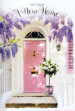 A tranquil yet joyful doorway, much like the hidden corners off Tollgate Road in Canning Town, is bathed in soft, late-afternoon light, creating a setting that feels both intimate and full of promise. At its heart stands a pink front door, tastefully painted in a muted pastel tone that radiates warmth without shouting for attention. The surrounding walls are washed in a chalky white, and a single shutter painted in matching blush ties the composition together, guiding the eye inward. Wisteria winds above and around the doorframe, tumbling down in luxuriant cascades of lavender and pale purple blooms. Each drooping cluster is full and almost cloud-like, suggesting a gentle perfume in the air, that familiar spring fragrance you might catch walking home from Star Lane or the nearby parks. At the foot of the door, a florist's grey tin bucket rests squarely on the step, brimming with an artfully arranged bouquet of white and cream roses. The roses are plush and full-headed, their petals soft and layered like folded silk, nestled among stems of delicate green foliage that peek through to add depth and freshness. Around the bucket, a pale pink ribbon is tied with care, its satin ends curling loosely, echoing the flowing lines of the wisteria above. Shafts of golden light filter through the blossoms and cast soft, patterned shadows on the doorstep, giving the impression of a calm, hopeful afternoon just as someone is about to cross the threshold. Everything in the scene-the colour palette, the textures, the gentle play of light-evokes a sense of welcome and tenderness, ideal for a new home flower delivery in Canning Town that celebrates fresh starts, heartfelt congratulations, and the comforting feeling of finally belonging.